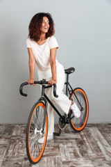 Poster - Vertical image of Pretty Happy african woman riding on bicycle