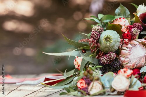 Fotografía Rustic wedding bouquet with white and bordeaux roses, peonies, poppy and greens on an aged wooden floor