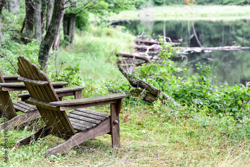 Empty Adirondack Chairs Along Wooded Shoreline Buy This Stock