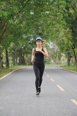 Wall Mural - Young fitness sport woman running on the road in the morning, Selective focus.