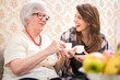 © Bojan - Cheerful granddaughter and her grandmother having together coffee cups at home.