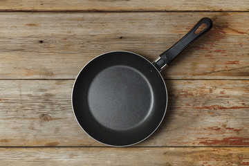 Empty frying pan on a wooden table, top view, rural style