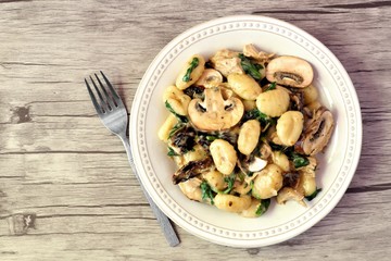 Wall Mural - Gnocchi with a mushroom cream sauce, spinach, chicken and sun dried tomatoes, top view on a wood background