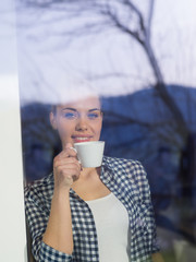 Wall Mural - young woman drinking morning coffee by the window