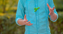 Man On The Azure Shirt And Blue Jeans Playing With Green Spinner Outdoors