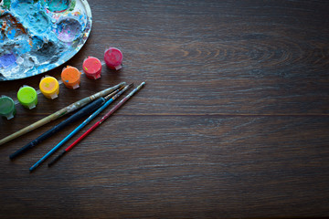 Art set, palette, paint, brushes on wooden background.