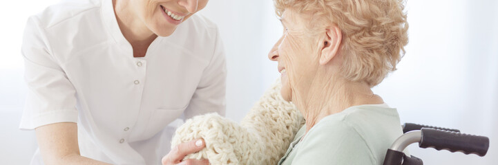 Nurse laying blanket on patient