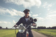 © ysbrandcosijn - Vintage motorcyclist in sunglasses and cap riding in countryside.