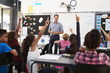© Monkey Business - School kids raising hands in elementary school class