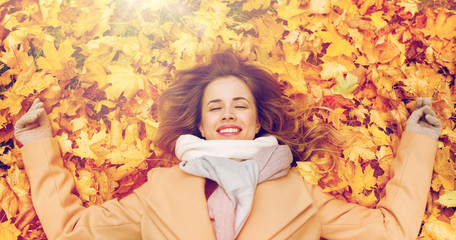 Wall Mural - beautiful happy woman lying on autumn leaves