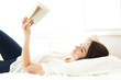 © Jessica Peterson/Tetra Images - Young woman reading book while lying on bed