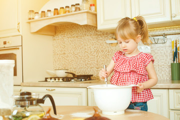 cute little helper girl helping her mother cooking in a kitchen. happy loving family are preparing b