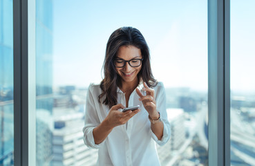 happy businesswoman using her mobile phone at office.