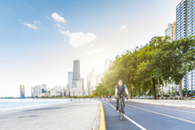 Man Cycling In Chicago With City On Background