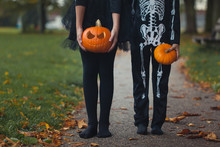 Body Shots Of Boy And Girl In Skeleton Outfits Holding Pumpkins