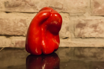 Sweet red pepper on the bricks wall background in a kitchen