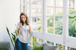 © BONNINSTUDIO/Stocksy - Woman using her phone having coffee in the morning at home.
