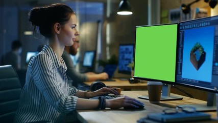 Poster - Beautiful Female Creative Professional Works on a Personal Computer with Mock-up Green Screen, Second Screen Shows 3D Ingame Graphics. She Works in a Creative Studio. 