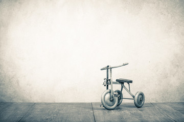 Old retro toy bicycle with three wheels. Vintage style sepia photo