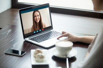 Woman making video call to girlfriend in cafe, communicating via app on laptop with close foreign best long distance friend, talking by web camera, using virtual chat, focus on screen, close up view