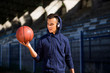 © Novak - Young teenager wearing blue hoodie and headphones looking at basket ball that he holds