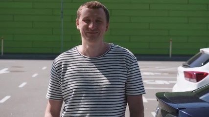 Leinwandbilder - Portrait young caucasian man posing near car on the parking. Happy smiling guy looking at the camera.