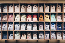 Shelves With A Lot Of Colorful Shirts Neatly Folded In The Store Clothes And Business Suits.
