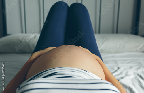 Fotografía Pregnant woman lying in bed touching her belly