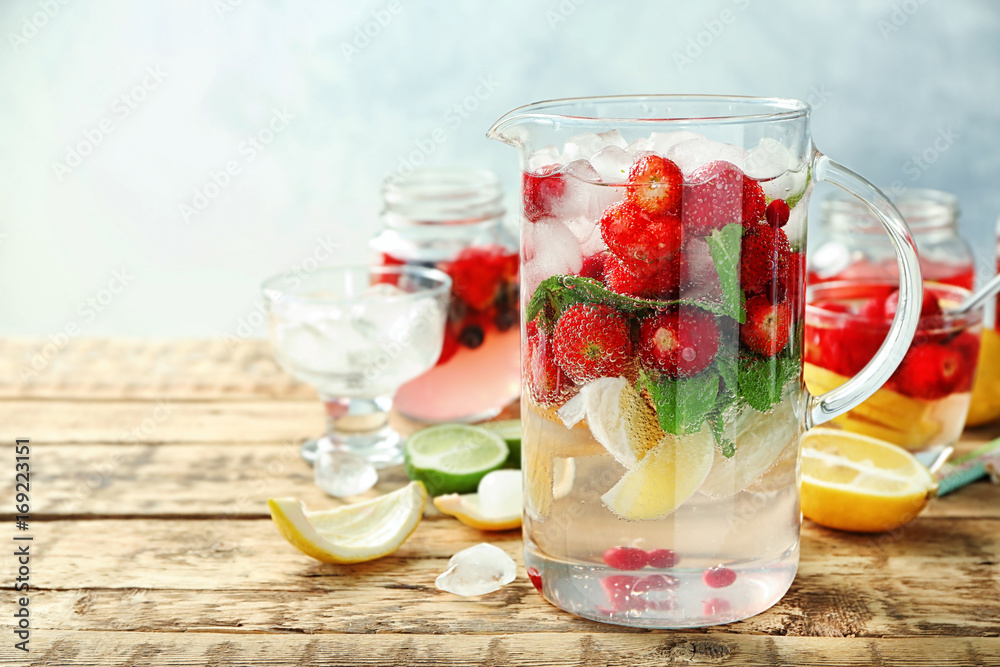 Jug with delicious strawberry lemonade on wooden table