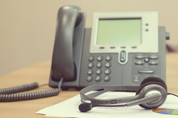 Wall Mural - close up soft focus headphone call centre hotline at computer office table with paperwork  and telephone for business and technology concept.