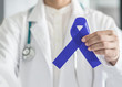 © Chinnapong - Dark blue ribbon for colon - colorectal cancer awareness on medical doctor's hand support