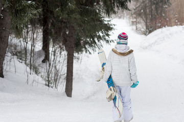 Wall Mural - Young girl snowboarder going down on a snowy mountain in the forest