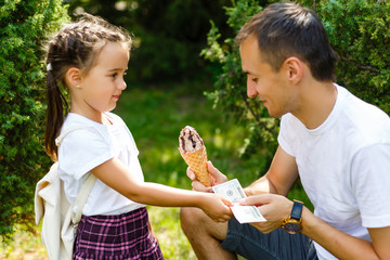 father and daughter eat ice cream. exchange of ice cream for the dollar