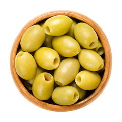 Wall Mural - Pitted and marinated green olives in wooden bowl. Fruits of the European olive, Olea europaea. Unripe table olives with yellow to green color. Isolated macro food photo close up from above over white.