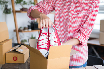 Wall Mural - business owner packing shoes in the box at workplace. freelance woman seller prepare product for packaging process at home.  Online selling, internet marketing, e-commerce concept