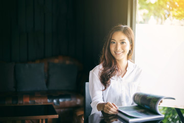 Asian women smiling and reading a book for relaxation at coffee cafe