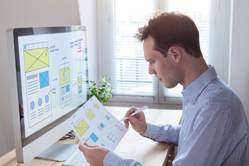 Wall Mural - website designer reading client specification, sketching responsive wireframe layout design