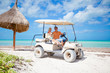 © travnikovstudio - Young father and two little kids driving golf cart on a tropical beach