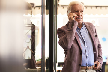 Wall Mural - Portrait of modern senior businessman speaking by phone indoors in cafe, copy space