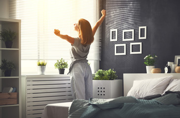 Wall Mural - young   woman woke up in the morning in the bedroom by the window with her back