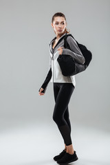 Wall Mural - Full length portrait of a fitness woman holding sports bag