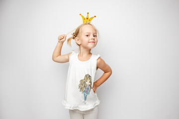 Beautiful little girl with paper crown posing on white background at home.