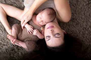 Canvas Print - Beautiful mother embracing with tenderness and care her newborn son, shot from above