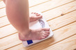 Female feet standing on mechanical scales for weight control on wooden background. Concept of slimming and weight loss