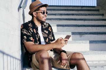Cheerful man using smartphone on stairs