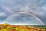 Fototapeta Tęcza - Stunning full rainbow with dramatic storm clouds in the English Peak District.