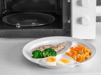 Poster - Plate with tasty organic food near microwave on table