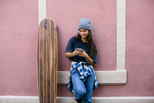 Portrait Of A Skater Girl Chatting On Phone In Front Of A Wall.