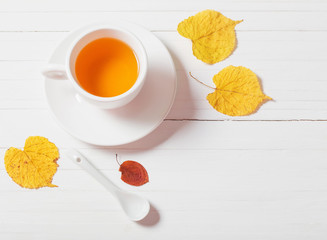 Poster - cup of tea with autumn leaves on wooden background