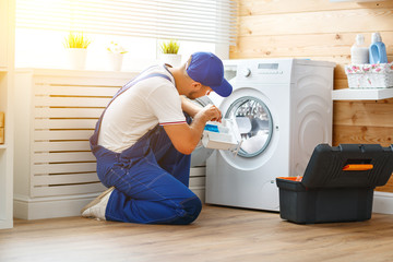 working man   plumber repairs  washing machine in   laundry